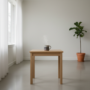 Wooden table with a mug and a plant in a minimalistic room.